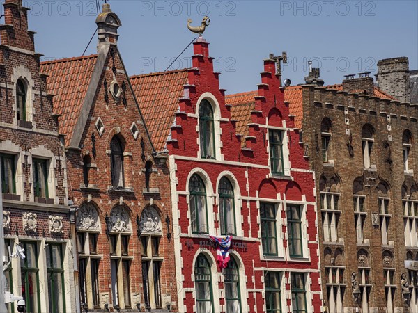 Row of colourful historic houses with gabled roofs and large windows under a clear blue sky,