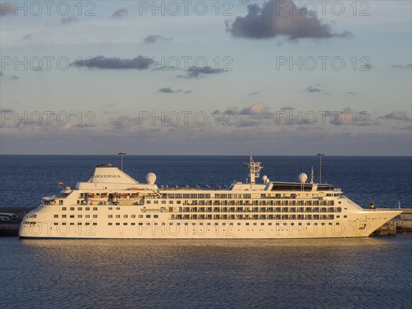 A cruise ship named Silver Spirit in the harbour at dusk, illuminated by the setting sun,