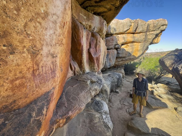 Young man looking at prehistoric depiction of woman on a rock, San rock paintings, Sevilla Art Rock