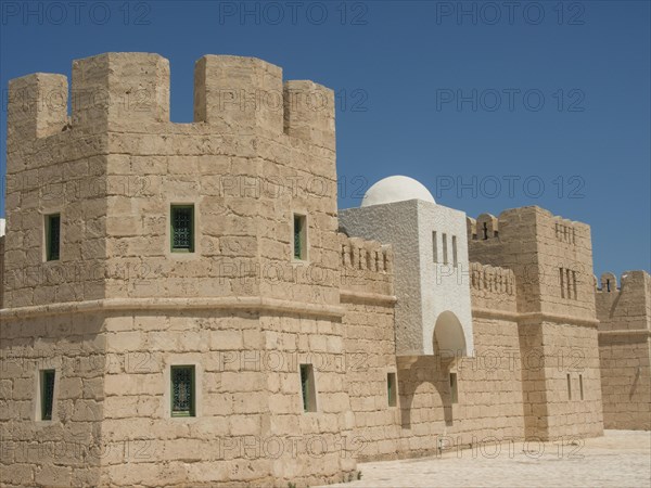 Stone fortress with high walls and towers under a clear blue sky, medieval ambience, Tunis in