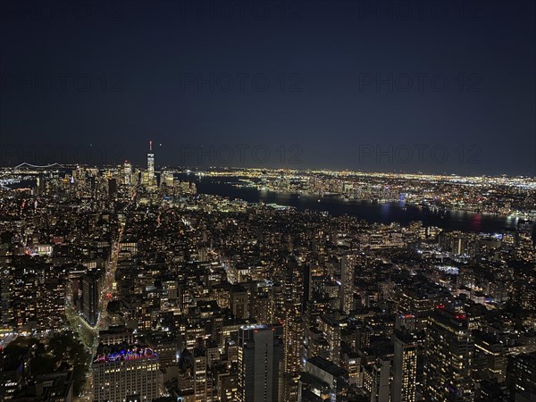Impressive night skyline of New York with illuminated skyscrapers and a river in the background,