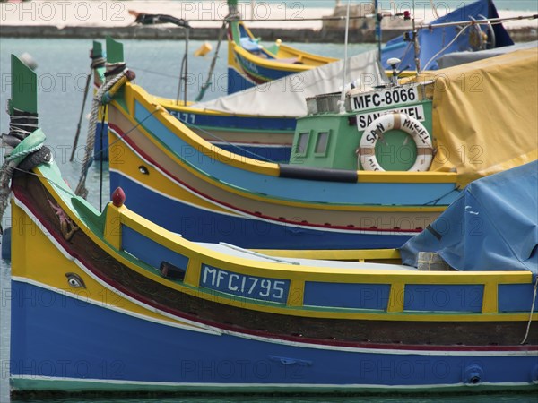 Close up of colourful fishing boats in the water, with bright colours and ropes, many colourful