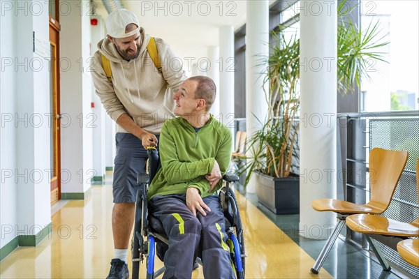Caucasian young man pushing the wheelchair of a friend with disability around the university