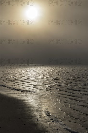 Morning sun shining through the dense fog reflecting on the waters of the Biloxi Bay at Front Beach
