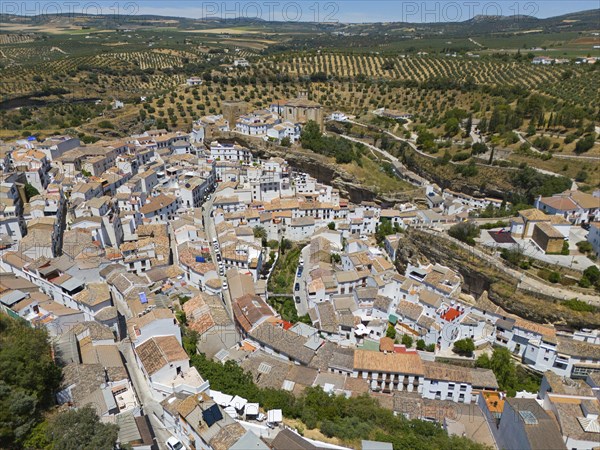 Aerial view of a picturesque town on a hill with serpentine roads and surrounding fields in summer,