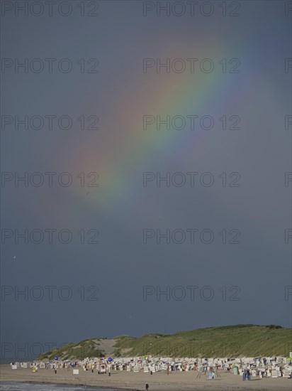A rainbow appears in the dark sky above a beach, Baltrum Germany