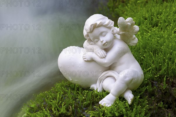 Porcelain angel figurine on moss by a waterfall