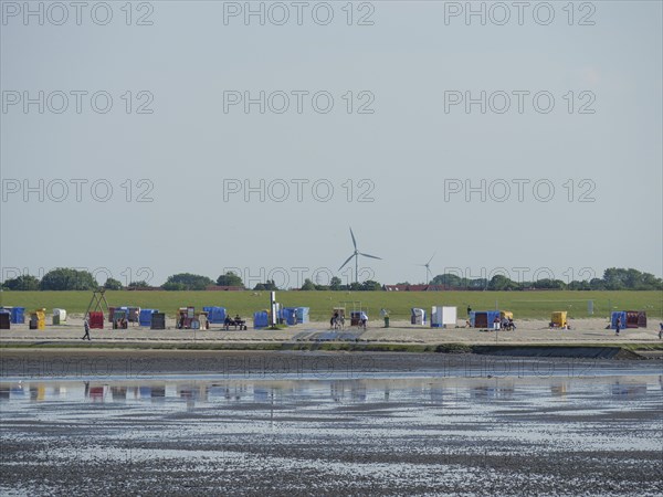View of a coastal landscape with colourful beach chairs and wind turbines, Baltrum Germany