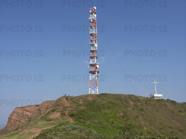 A large transmission mast stands on an overgrown hill under a clear sky. A technical highlight in