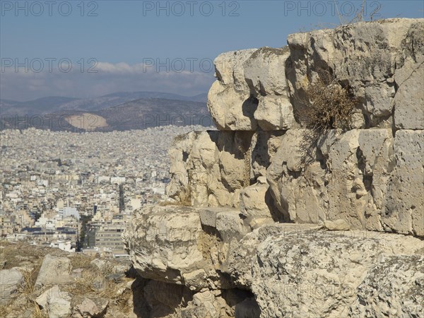 Large ancient stones on a hill overlooking a modern city under a blue sky, Ancient buildings with