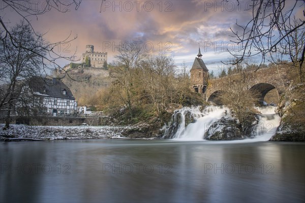 Beautiful landscape in winter with ice and snow. Waterfall of the river Elz near the castle