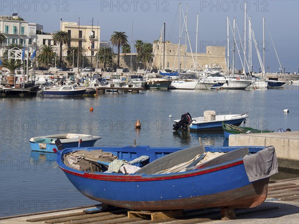 Harbour with fishing boats and sailing boats in the water, palm trees and buildings in the