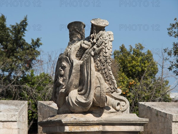 Stone sculpture of an eagle with outstretched wings in a natural setting with trees, the town of