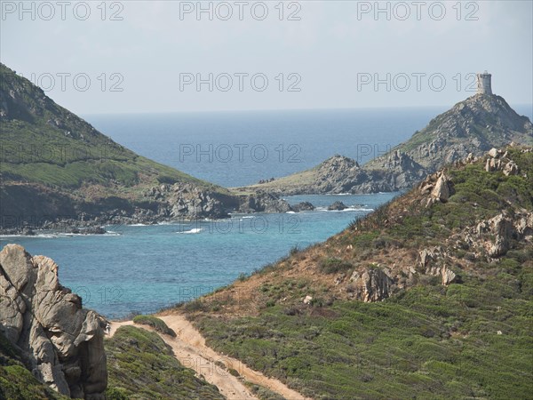 Path leading along a rocky coastline with turquoise sea and an old fortress, Corsica, Ajaccio,