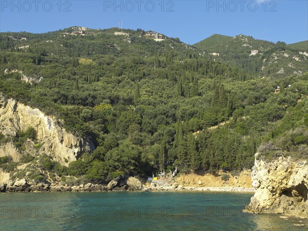 Lush hills stretch down to the coast with clear blue water and a small beach, beach on the island