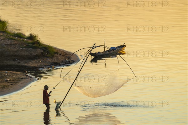Fisherman with a sinking net at sunset on the Mekong, Luang Prabang, Laos, Asia