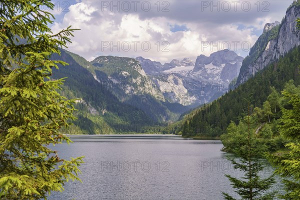 Spectacular lake surrounded by steep mountains and dense forest under a cloudy sky, turquoise green
