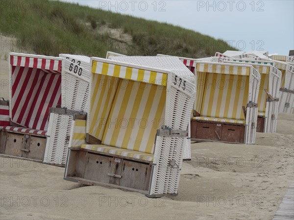 Colourful beach chairs in a row on the sandy beach, surrounded by dunes, pleasant weather without