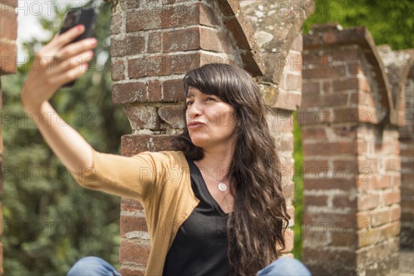Young hispanic woman in casual clothing focused on conversation with smartphone in a peaceful