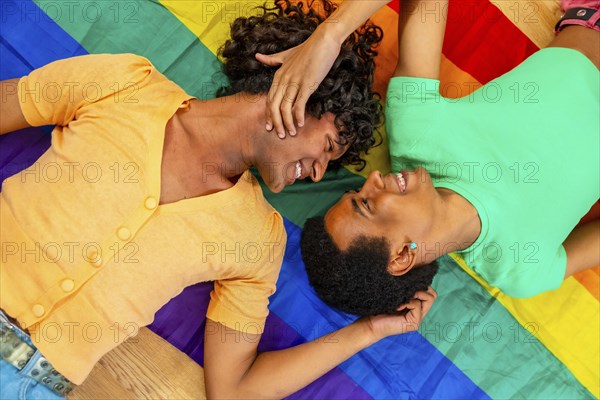 Top view photo of a latin male young gay couple in love over a LGBT rainbow flag smiling