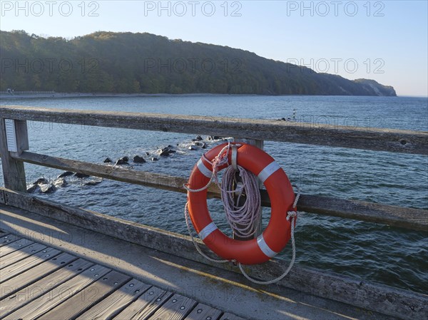 Lifebuoy on a wooden railing on the pier overlooking the calm sea, Ruegen, Germany, Europe