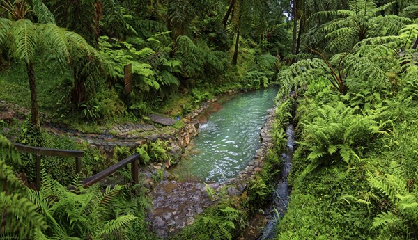 Hiking trail with hot natural thermal spring in Caldeira Velha in a lush green environment with