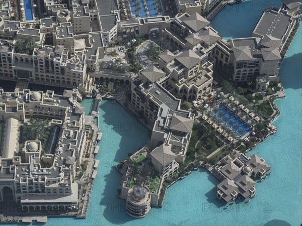 Aerial view of a large building complex with several swimming pools and turquoise-coloured water in