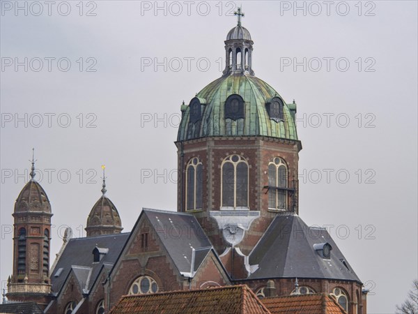 A church building with a central green dome and two smaller towers, under a cloudy sky, historic
