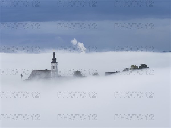 Church tower rises out of the morning mist, Frauenberg pilgrimage church, near Leibnitz, Styria,