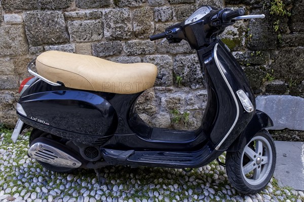 Black Vespa in front of an old stone wall, Rhodes, Greece, Europe