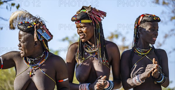 Hakaona woman with traditional kapapo hairstyle, clapping and laughing, Angolan tribe of the