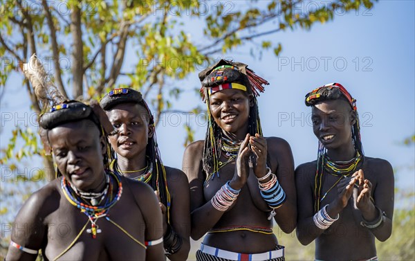 Hakaona woman with traditional kapapo hairstyle, clapping and laughing, Angolan tribe of the