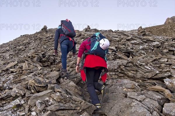 Two alpinists with heavy rucksacks climbing through a scree field, Bernese Alps, Kandersteg,