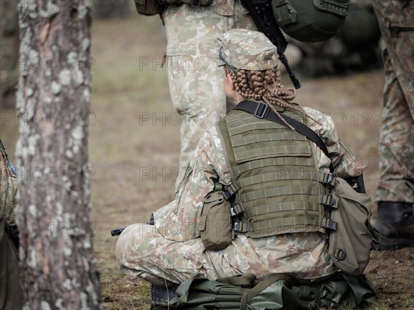 Young Lithuanian female reserve soldier sitting on the floor during her lunch break during her