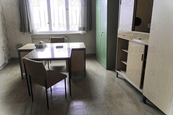 Simply furnished office with desk, chairs, filing cabinet and large window,