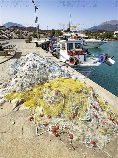 In front fishing nets nets of fishermen behind moored fishing boat moored to quay wall in harbour