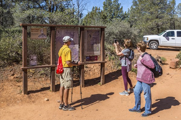 Woman takes photo of trail map before starting a hike in Sedona, Arizona, USA, North America