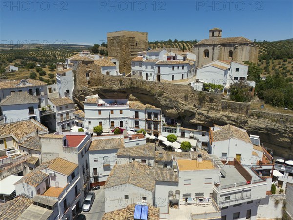 Aerial view of a Spanish village with white buildings, historic buildings, churches and olive
