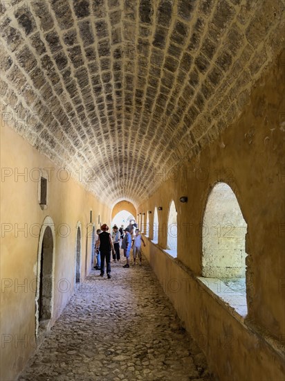 Archway with left doors to former monastery cell monk cells in the background tourists in UNESCO
