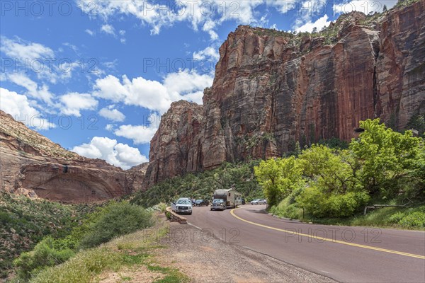 Recreational vehicle passes tourists at an overlook next to a blind arch along the Zion Park