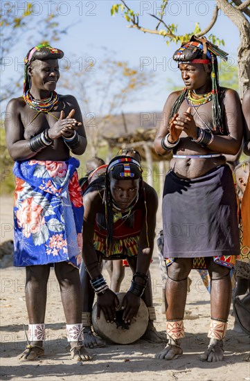 Hakaona woman with traditional kapapo hairstyle, clapping and drumming, Angolan tribe of the