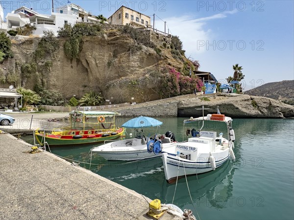 Three boats in small harbour marina of Agia Galini, right fishing boat ship excursion boat for