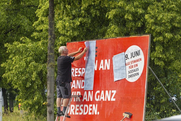 A poster artist renews a large SPD campaign poster for the elections on 8 June 2024, in the city