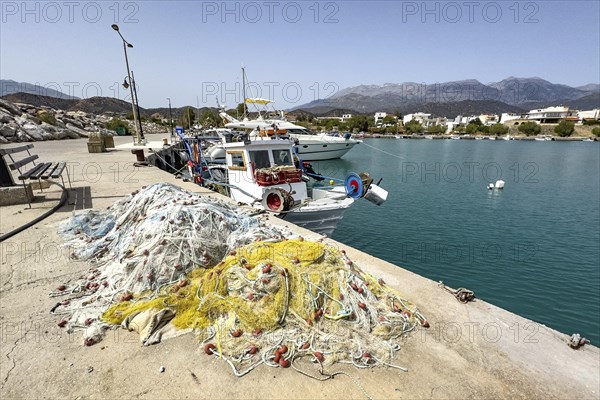 In front fishing nets nets of fishermen behind moored fishing boat moored to quay wall in harbour