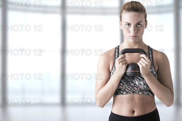 Fit woman working out with a kettlebel and similingl in a gym