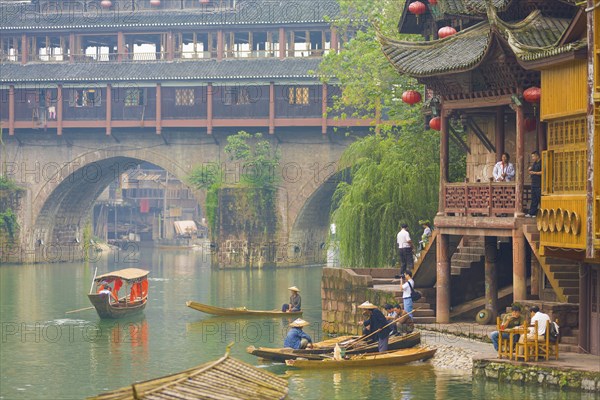 Fenghuang, China, September 10, 2007: Tourists and boats hang around riverside at the Phoenix Hong