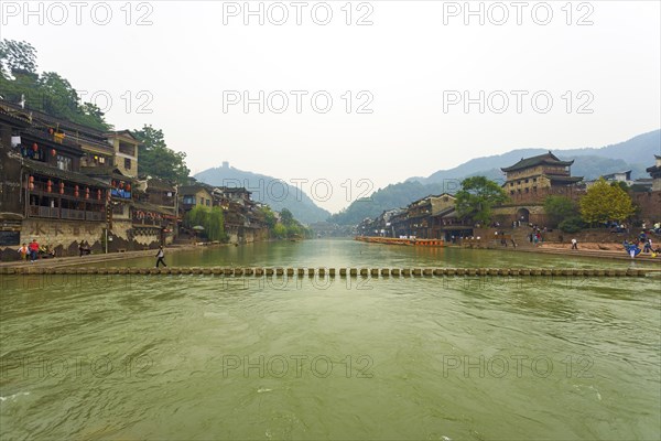 Fenghuang, China, September 10, 2007: A stepping stone bridge spans the Tuojiang River which cuts