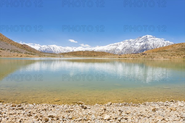 A pristine alpine lake reflects the surrounding Himalayan mountains. The lake is a pilgrimage point