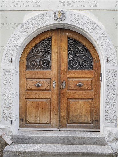 Antique wooden door with ornately carved archway and metal grilles in a historic building, lindau,