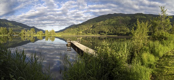 Footbridge leading into a lake, Gaishorner See in the evening light, panoramic view, Gaishorn am